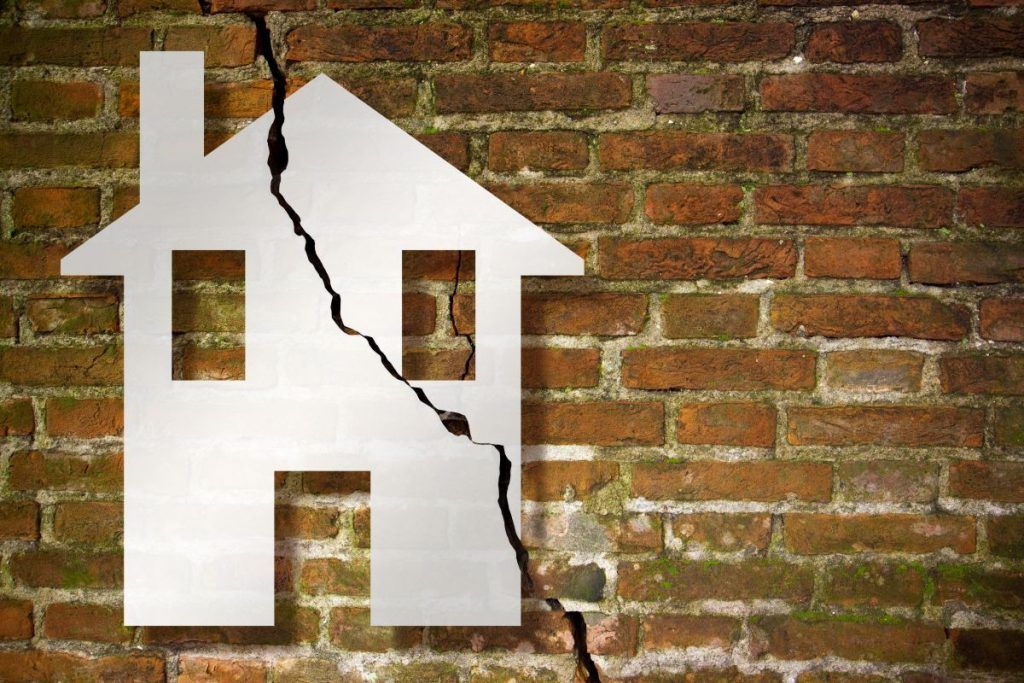 Cracked old and aged broken brick wall with a house drawn on it concept image